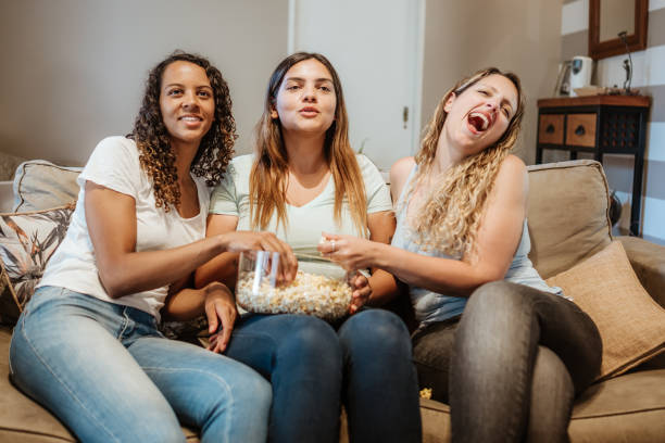 istock Friends Laughing and Sharing Popcorn on a Couch 2106943247