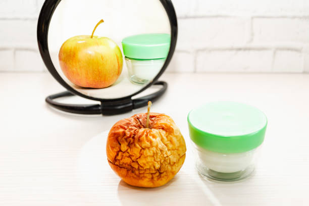 istock wrinkled apple is reflected in mirror as fresh, healthy. Concept: skin care, plastic surgery 2106980139