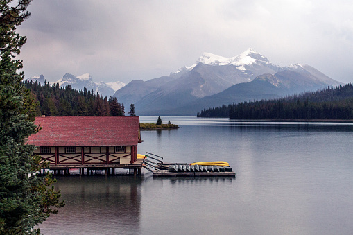 Boathouse on lake below mountains and storm, Maligne Lake, Jasper National Park
