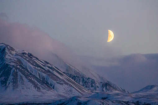 Early morning light on mountains in winter, moon in distance