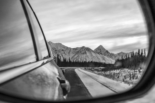 View down highway to mountains from side mirror