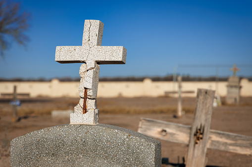 An old stone cross on a grave stone at La Isla Cemetery near Fabens, Texas.