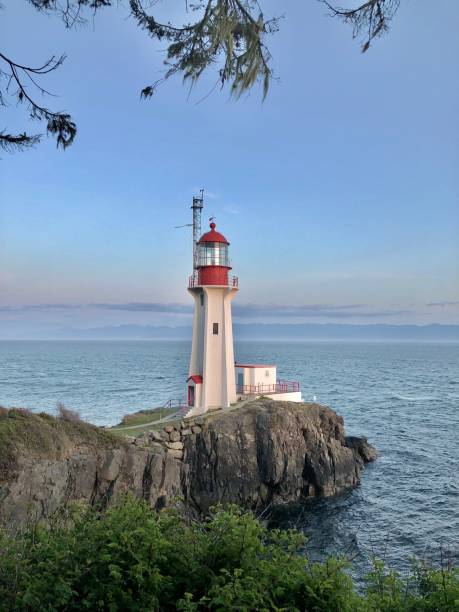 istock Lighthouse stands on rock bluff at sunset 2107000600