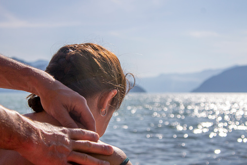 Portrait of man massaging woman's shoulders on edge of ocean