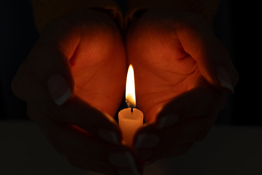Cupped hands with burning candle