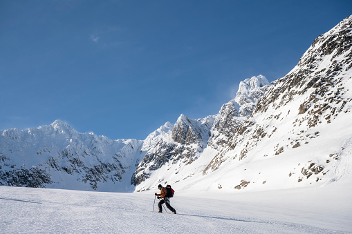 Ski mountaineer ascends snowcapped mountain above glacial plain