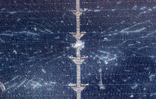 Close up view of damaged broken solar panel tempered glass cell. Stone dent in the middle with spiderweb cracks around.