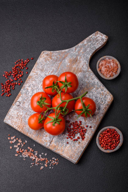 istock Fresh red cherry tomatoes on a branch on a dark concrete background 2107233573