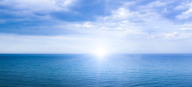 Calm windless ocean with the sun on the horizon. Seascape.