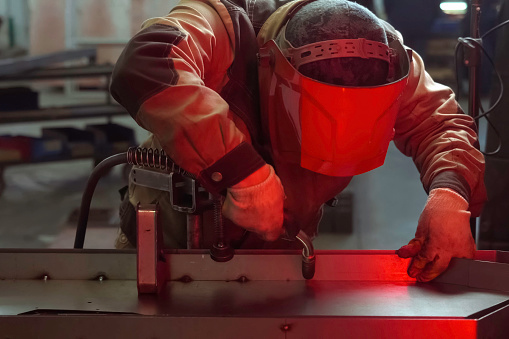 A welder in a mask welds stainless steel parts.