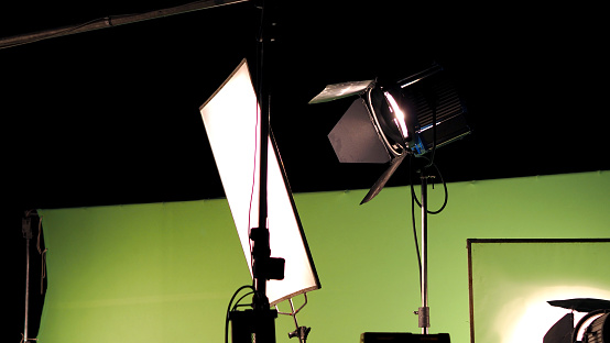 Big studio Film lighting kit 5000 watt with soft box on tripod and professional green screen background chroma key post production technique shooting or filming for movie or video commercial set up.