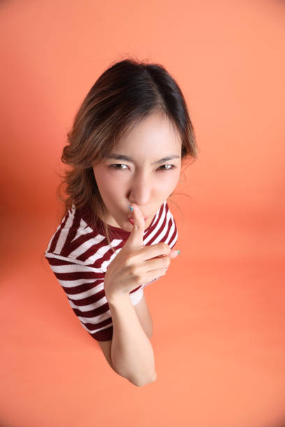 The young Asian woman in casual clothes with gesture of  casual pose on the orange background. Close-up shot, Top view shot