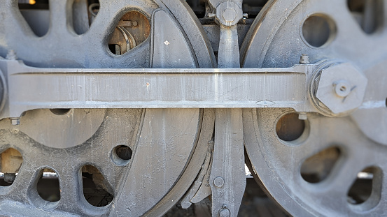 The heavy steel rail wheel pair and coupling rod of an old train. close-up