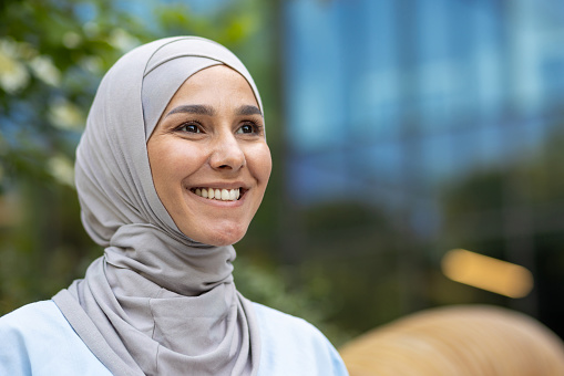 Elegant and modern young woman wearing a hijab against an urban backdrop, exuding confidence and style.