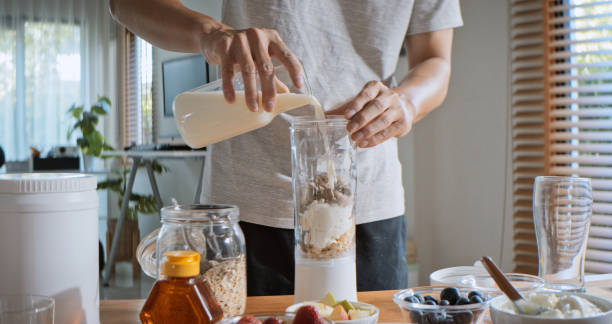 istock Young adult Asian man prepare and make protein shake drink, mixed fruit cereal juice, using blender mixer. Fitness dietary activity, healthy diet lifestyle, health care nutrition concept 2107379911