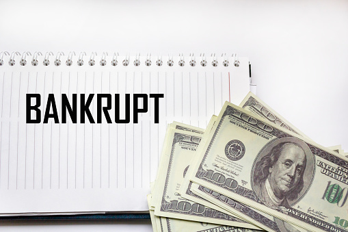 BANKRUPT - the word on the background of money dollars, notepad. Business concept