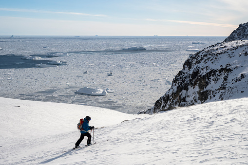Ski mountaineer ascending snowcapped mountain above glacial plain