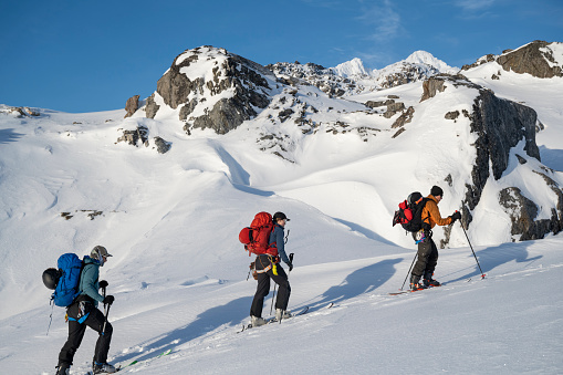 Ski mountaineers ascending snowcapped mountain across glacial plain