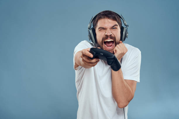 istock Man in headphones controller in hands playing game console lifestyle emotions blue background white t-shirt 2107404985