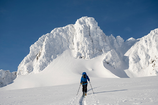 Ski mountaineer ascending snowcapped mountain across glacial plain