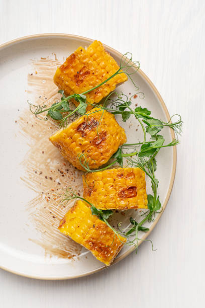 istock Overhead view of half plate with grilled sliced maize or corn and microgreens served on table 2107411791