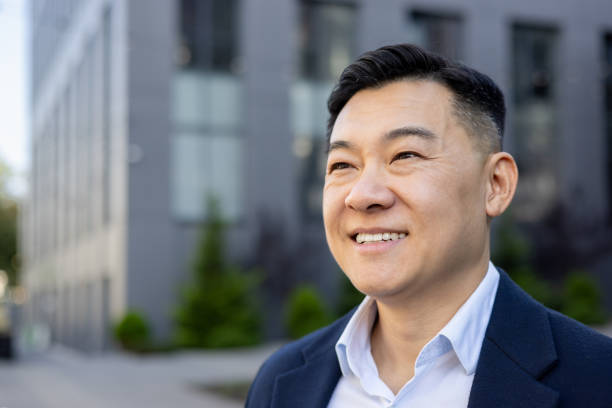 istock Confident asian businessman smiling outdoors with modern building 2107425975
