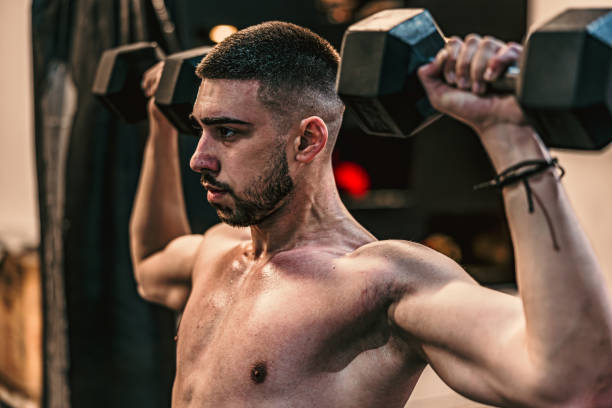 istock Man raising metallic dumbbells in a gym 2107432808
