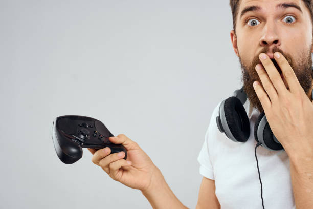 istock Man with gamepad headphones playing leisure technology white t-shirt light background 2107432818