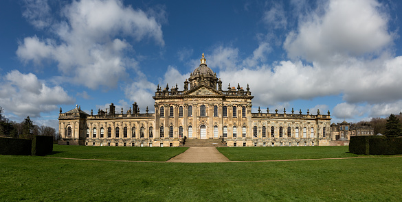 Castle Howard, York, UK - March 23, 2024.  A landscape panorama of the front facade of Castle Howard Stately House in the Howardian Hills with sunshine and blue sky