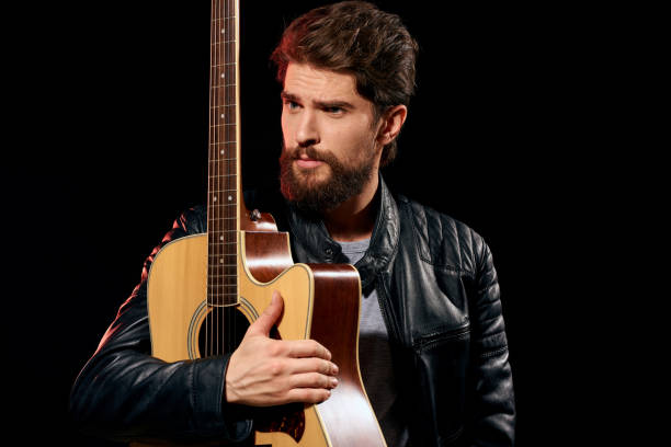 A man with a guitar in his hands leather jacket music performance rock star modern style dark background. High quality photo