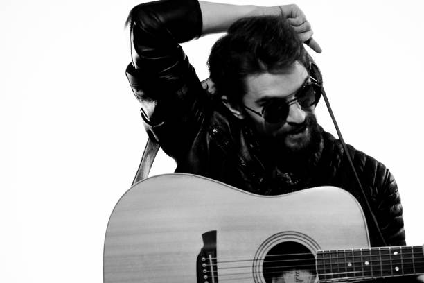 istock A man plays the guitar in a black leather jacket with sunglasses on a light background 2107447455