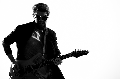 Cheerful male musician in leather jacket with sunglasses guitar performing. High quality photo