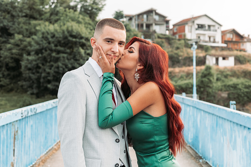 Young teenage couple dressed up for the prom. Girl kissing her prom gate on the cheek