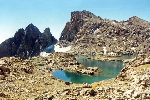 A gem turquoise colored unnamed lake with 12956ft Scylla and 12,661 The Three Sirens for an adventurous background as viewed from the rugged terrain near Ionian Basin of Kings Canyon National Park.