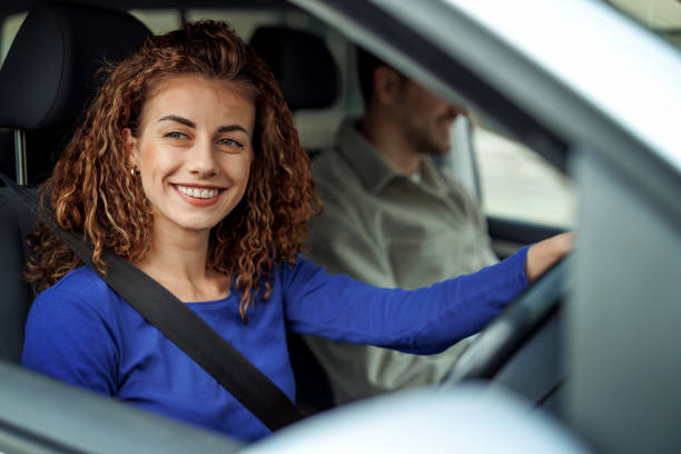 istock Smiling beautiful woman driving car with her husband 2107485413