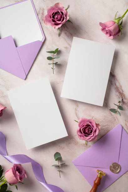istock Flat lay composition with blank wedding invitation cards, purple envelopes, roses on marble desk table. Top view. 2107491748