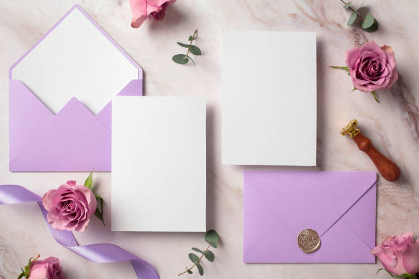 istock Blank white invitation cards with violet envelopes and roses buds. Wedding stationery set. Flat lay, top view, copy space. 2107495411