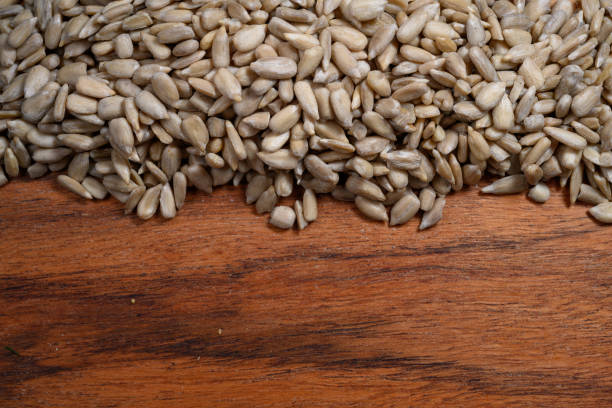 Sunflower shelled seeds on wooden board, top view, close-up