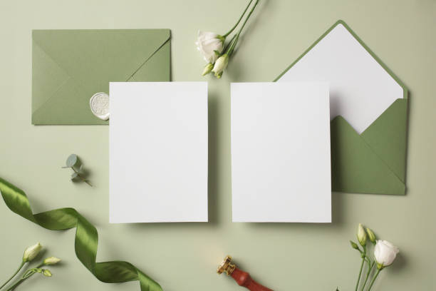 istock Flat lay composition with blank paper cards wedding invitations, envelopes, wax stamp, flowers on green background. 2107508389