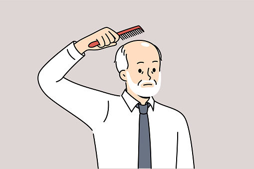 Elderly balding man holds comb over head, upset about hair loss due to old age. Balding businessman in white shirt and tie is thinking of hair transplant operation on forehead and occiput