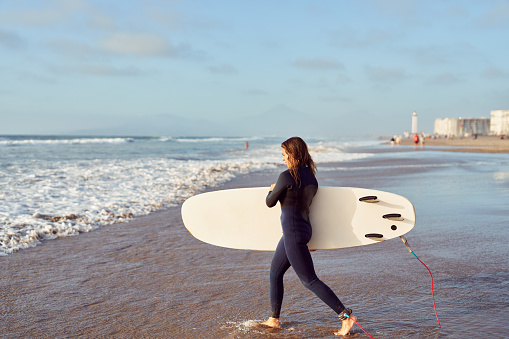 latin women getting into the ocean with surfboard to ride the waves in La Serena