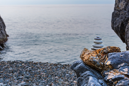 Pyramid-shaped tower created with beach stones, Apacheta, on a rock and with the Mediterranean Sea in the background, Nerja.