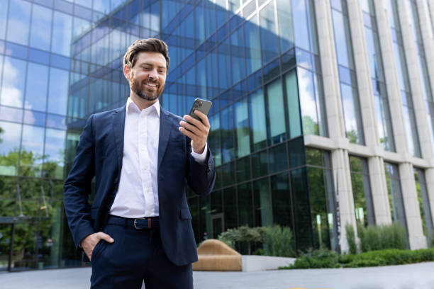 istock Confident businessman using smartphone outside modern office building 2107562068
