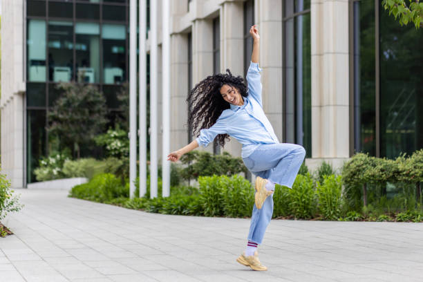 istock Joyful young woman dancing outdoors with a lively urban backdrop 2107570565