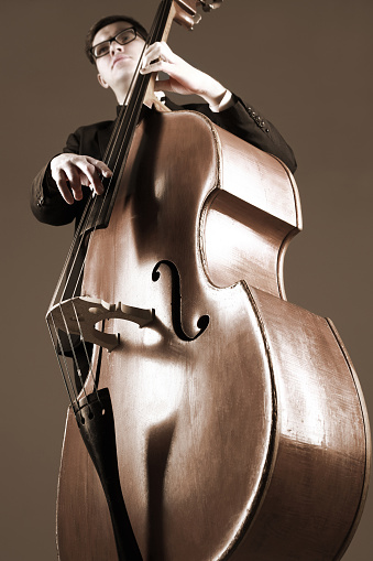 Double bass player contrabass playing pizzicato. Classical musician jazz bassist. Focus is on the strings