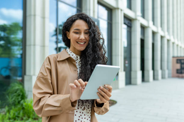 istock Professional hispanic businesswoman using tablet on break outside office 2107602421