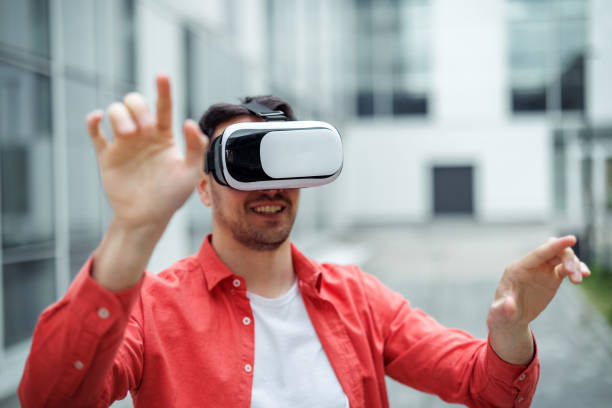 istock Handsome casually clothed man using VR goggles outdoors 2107606099