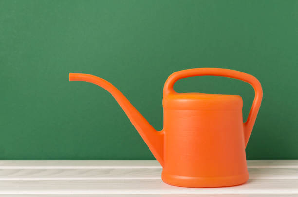 Orange watering can on wooden table