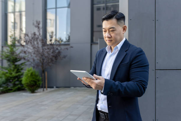 istock Professional asian businessman using tablet outside modern office building 2107670715
