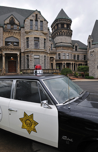 Mansfield, OH, USA, Sept. 12, 2023: A classic police car sits outside the historic Ohio State Reformatory in Mansfield, a former prison that's now a popular tourist attraction and filming location for movies including The Shawshank Redemption and Air Force One.
